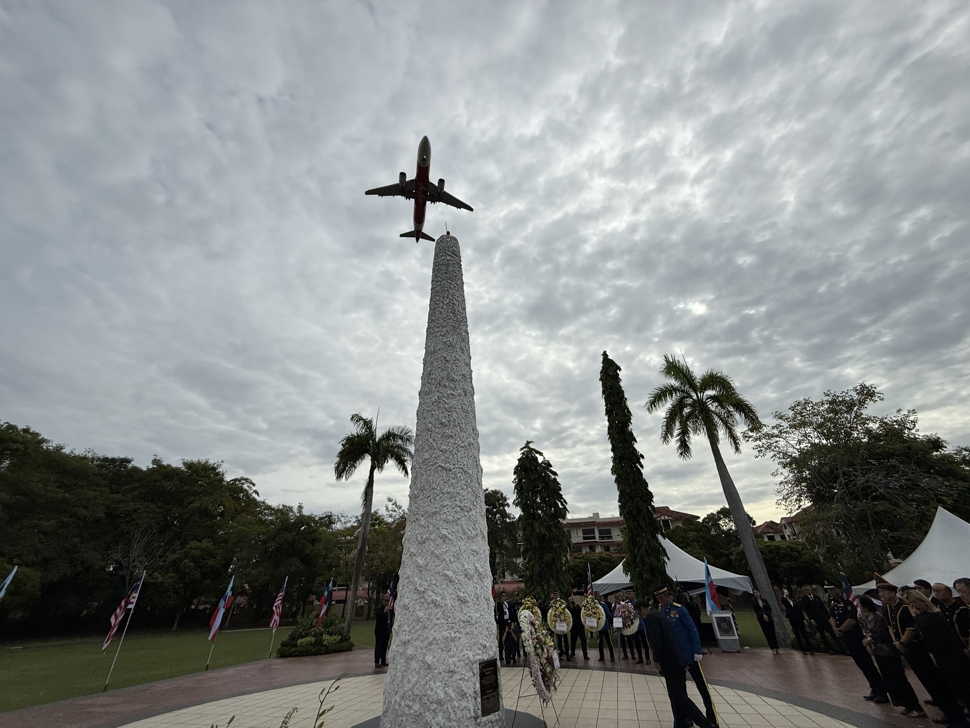 An aircraft flies over the Double Six Monument at the crash site in Sembulan, Kota Kinabalu, as a senior officer lays a wreath to honour the leaders who perished in the June 6, 1976 incident. – BorneoVox, June 6, 2025